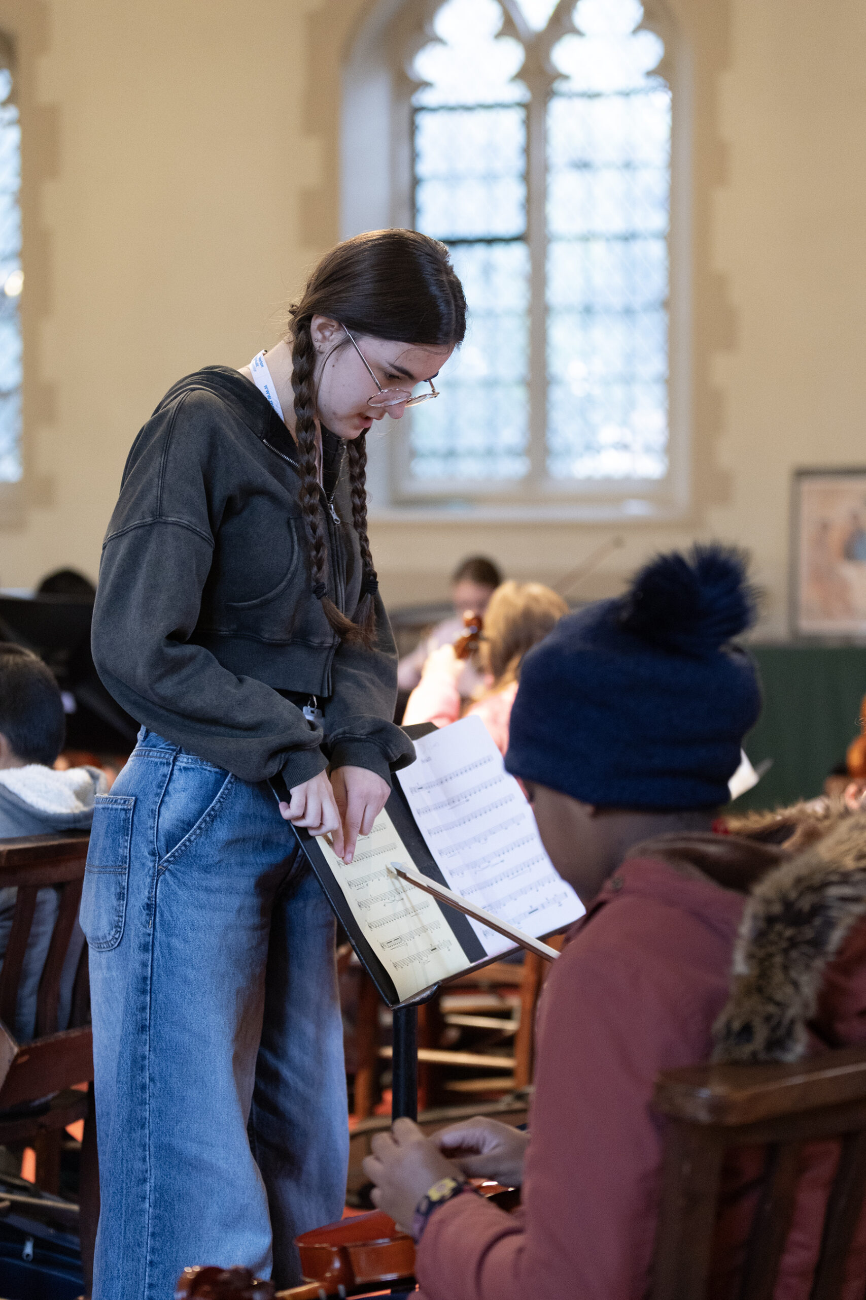 A teenage musician helping younger musicians in a rehearsal.