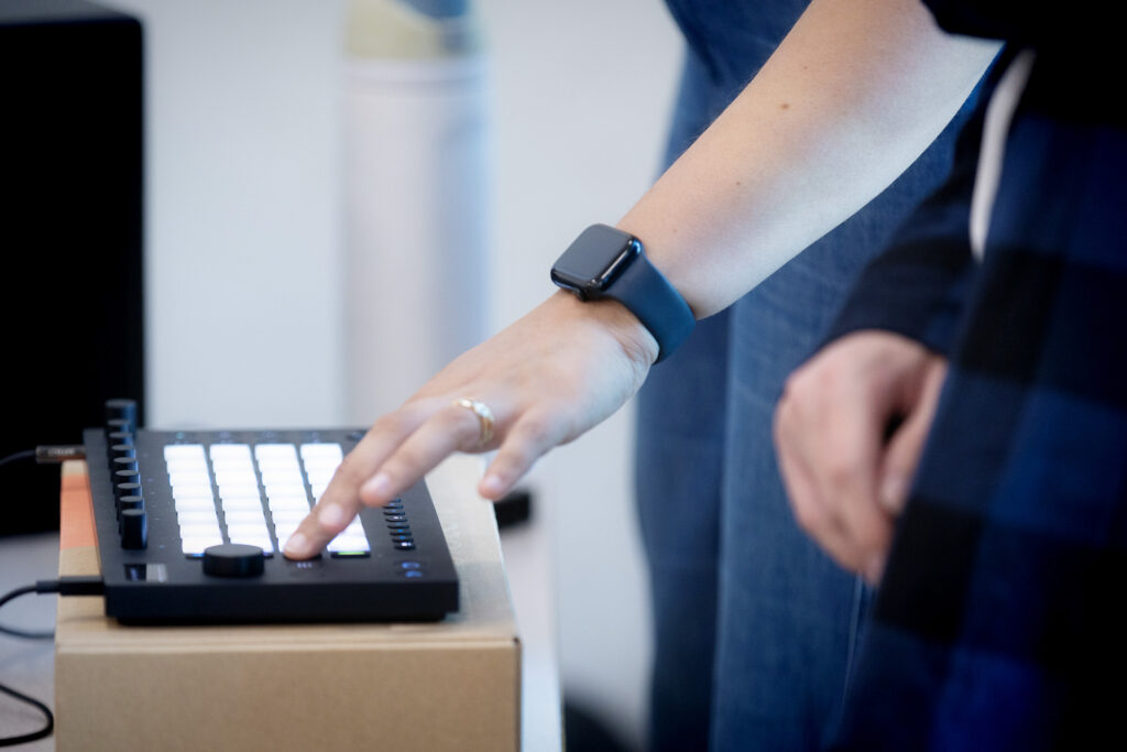 A hand pressing buttons on electronic pads during a Resonance session.