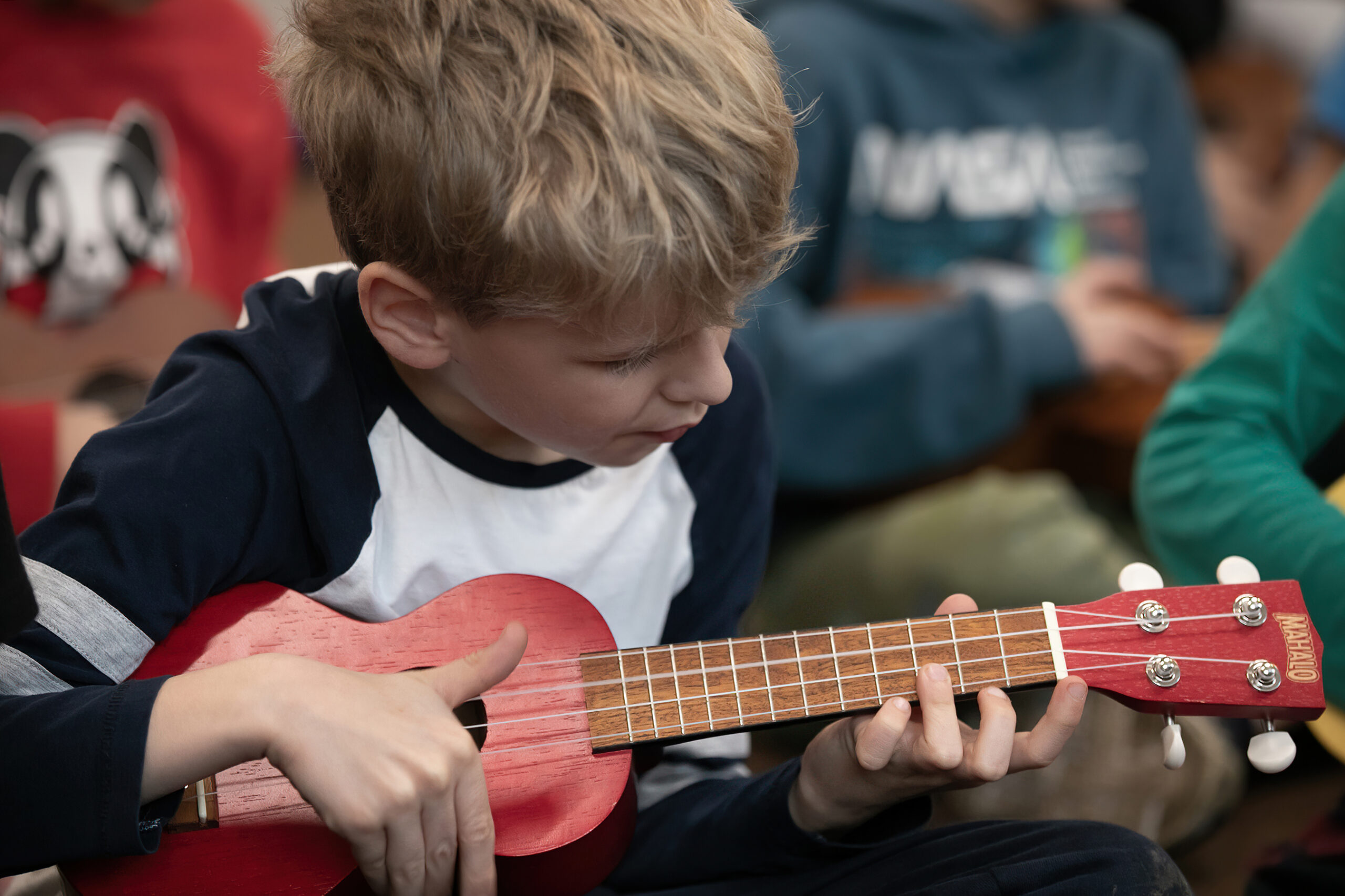 A boy playing ukulete during a class.