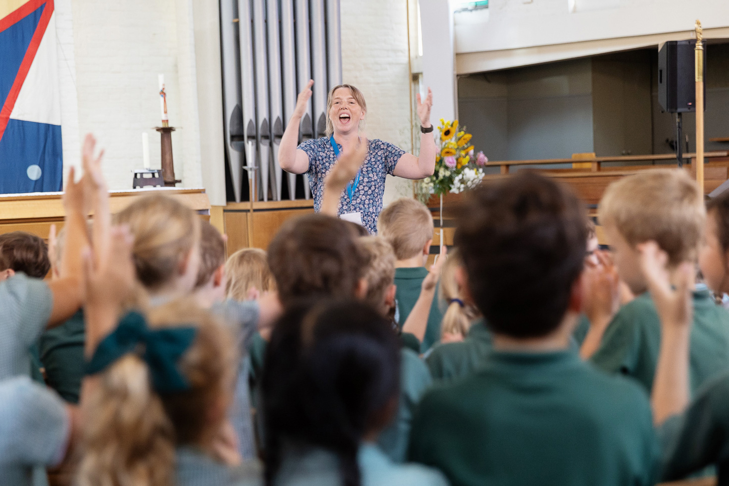Music tutor leading a group of school children singing at the Mini Musicians Festival