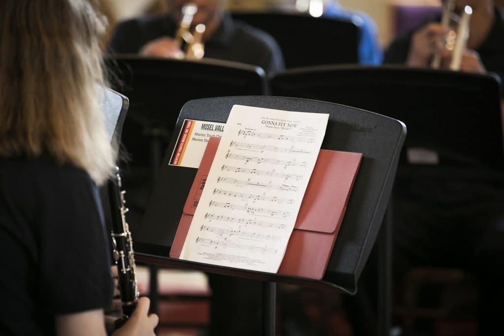 A musician sits with their back to the camera, holding an instrument.
