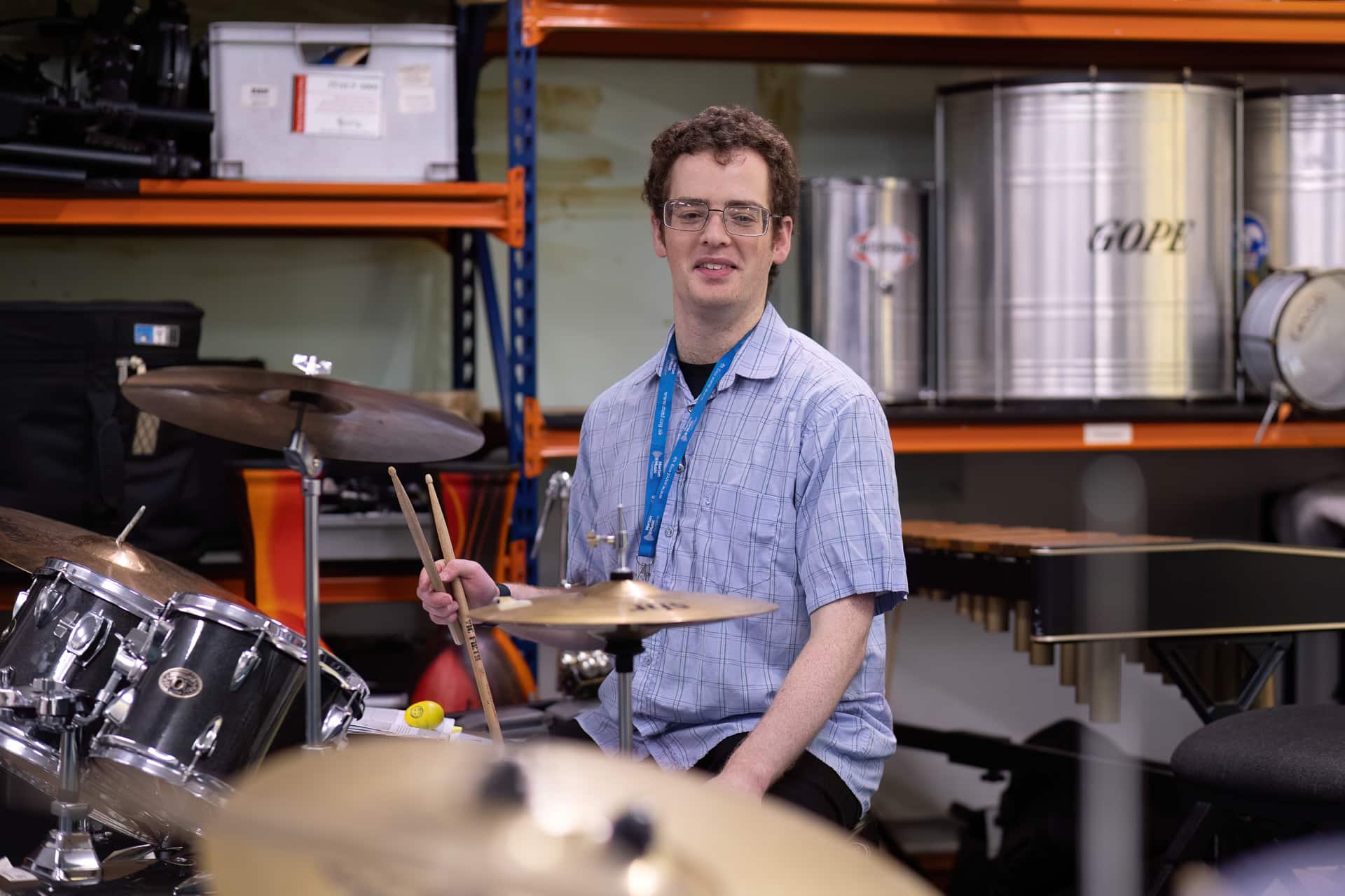 Aidan, an MMF percussion tutor, sits at a drum kit