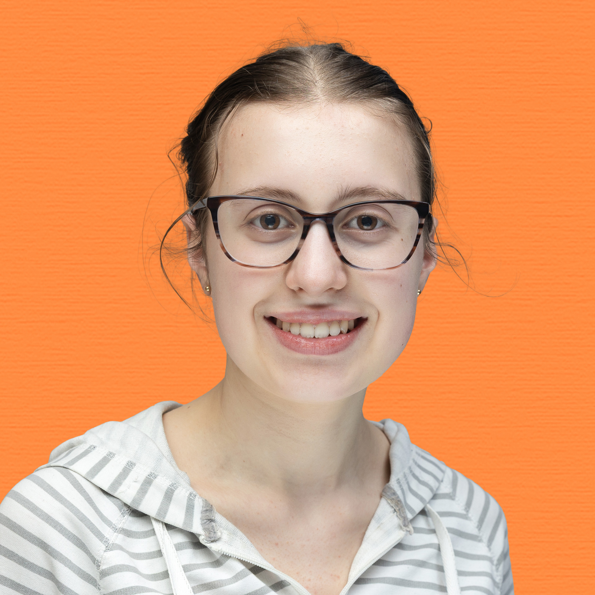A young woman with glasses and brown hair tied back, wearing a grey and white striped hoodie, smiles at the camera in front of an orange textured background, proudly representing the Youth Council.