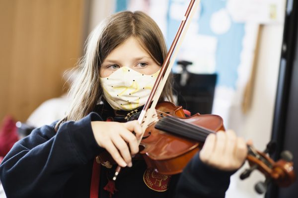 photo of a girl wearing a mask and playing the violin